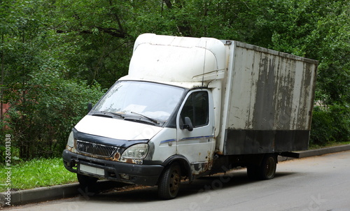 An old white broken truck is abandoned near the lawn, Iskrovsky Prospekt, St. Petersburg, Russia, August 2022 photo