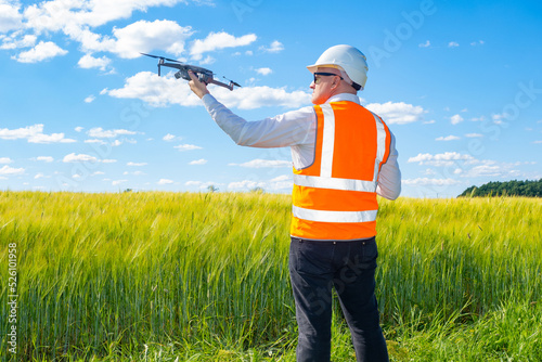 Surveyor engineer is holding drone. Surveyor with quadcopter on green field. Concept - builder uses drone for topographic expertise. Surveyor engineer with drone surveys area before construction