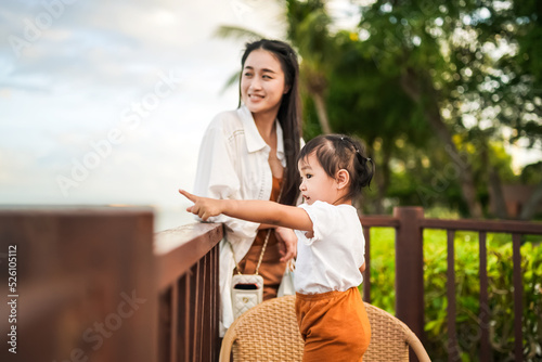 Asian cute little girl and her soft blurred mother taking a view on the beach during sunset.