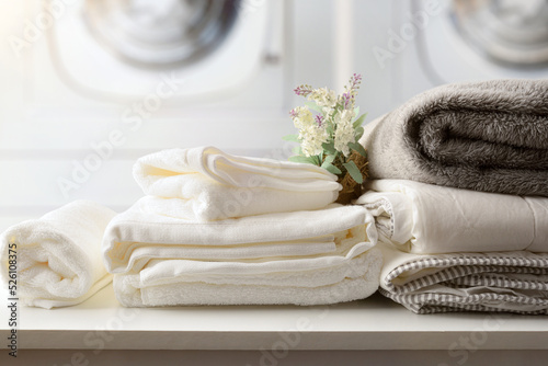 Foto Self-service laundry with textiles on bench and washing machines detail