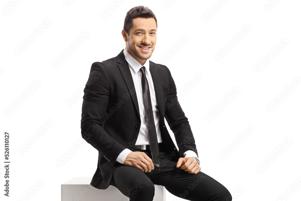 Businessman sitting on a white cube and looking at camera Businessman sitting on a white cube and looking at camera