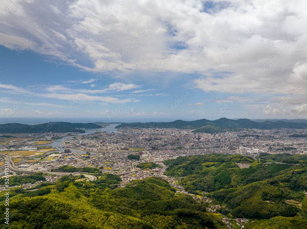 Fototapeta premium Aerial view of sprawling city at base of green hills
