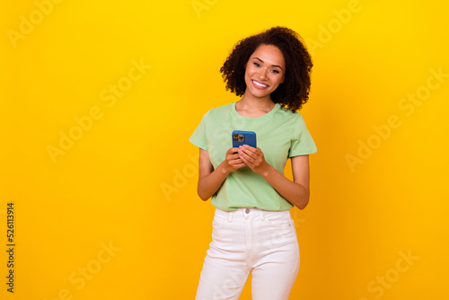 Photo of pretty adorable girl dressed green t-shirt chatting modern device empty space isolated yellow color background