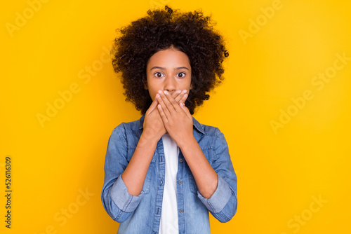 Portrait of attractive worried teen age small little girl closing mouth oops isolated over vibrant yellow color background