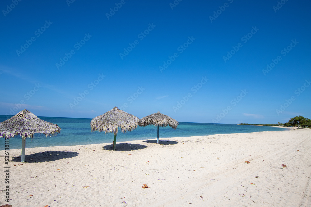 Paradise beach in Cuba with palm umbrella and clear blue water. 