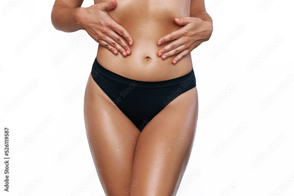 Naklejka premium Cropped shot of young slender tanned woman smearing her body with cosmetic oil isolated on a white background. Cosmetology, massage, spa products. The girl moisturizes the skin after sunburn