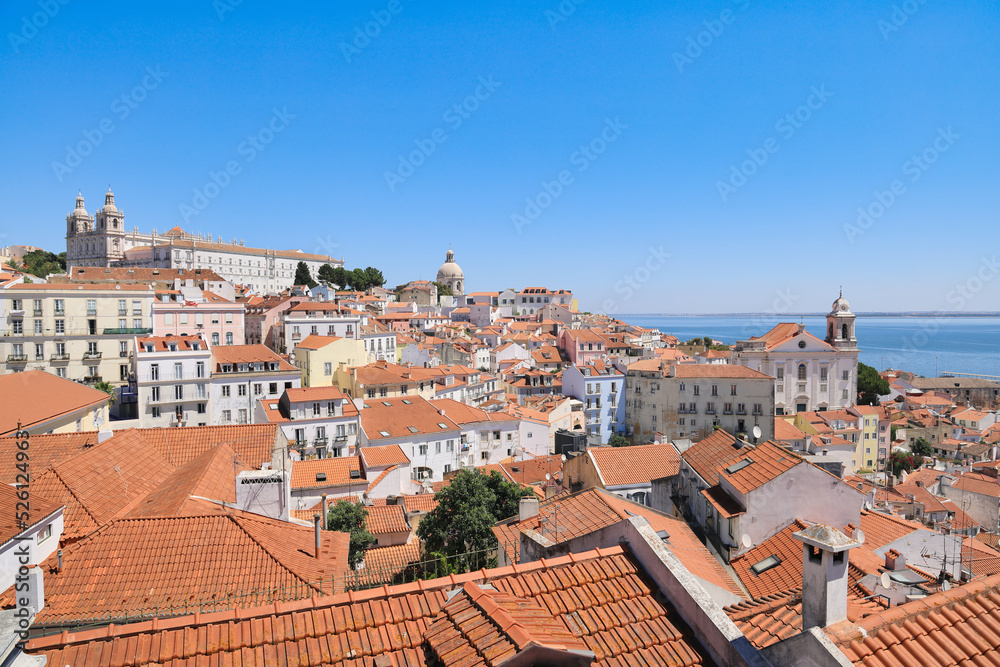 Lisbon, capital city of Portugal. The Alfama, oldest neighborhood of Lisbon with red tiled roofs, old churches and Tagus river. Famous postcard view. Copy space, place your text.