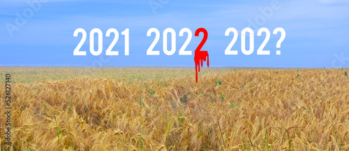 Years 2021 2022 and 202? on the field of yellow wheat and blue sky. The number 2 in 2022 is in the blood. New year 2023 concept of war in Ukraine photo