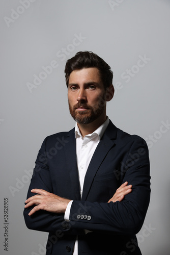 Portrait of handsome bearded man in suit on light grey background