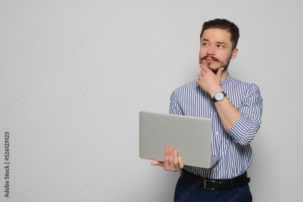 Pensive man using laptop on light grey background. Space for text Pensive man using laptop on light grey background. Space for text