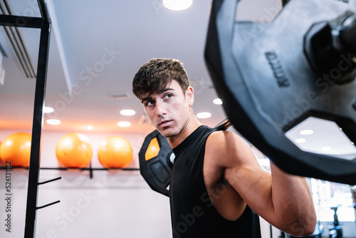 Male weightlifter with barbell looking away