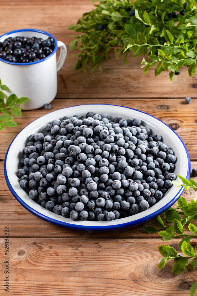 Frozen blueberries in a metal bowl on wooden table Frozen blueberries in a metal bowl on wooden table