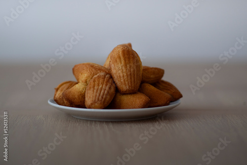 Top down view of freshly baked madeleine sponge cakes on a white background with red spots.