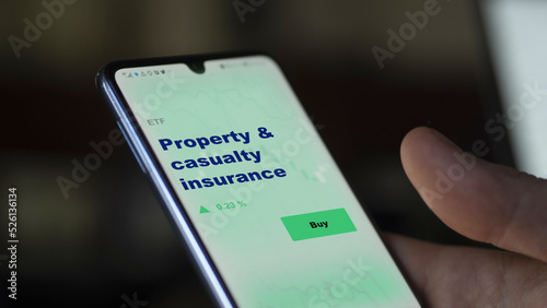 An investor's analyzing the insurance coverage fund on screen. A phone shows the ETF's prices property & casualty insurance photo