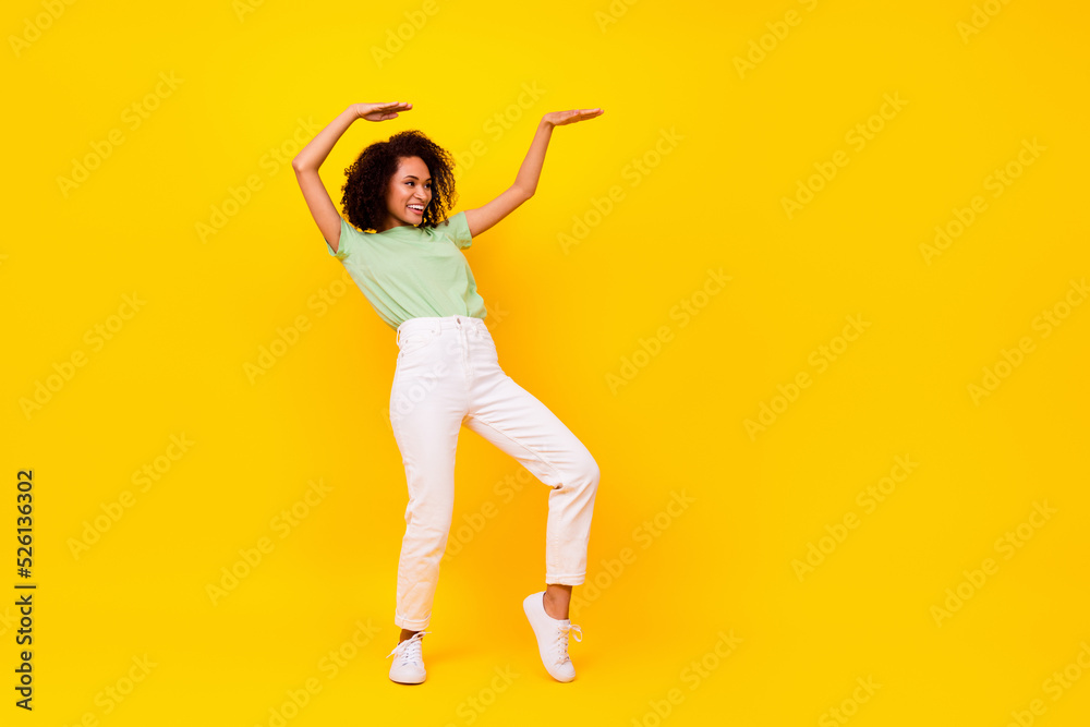 Full length photo of sweet adorable girl dressed green t-shirt dancing looking empty space isolated yellow color background Full length photo of sweet adorable girl dressed green t-shirt dancing looking empty space isolated yellow color background