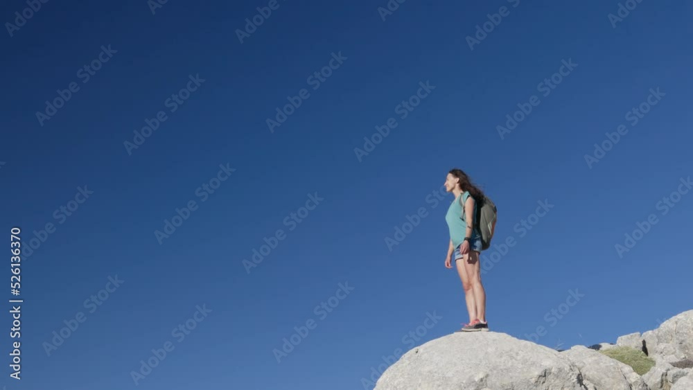girl stands against the background of the blue sky. joyful young girl stands on top of the mountain. a trip to the mountains. girl stands against the background of the blue sky. joyful young girl stands on top of the mountain. a trip to the mountains.