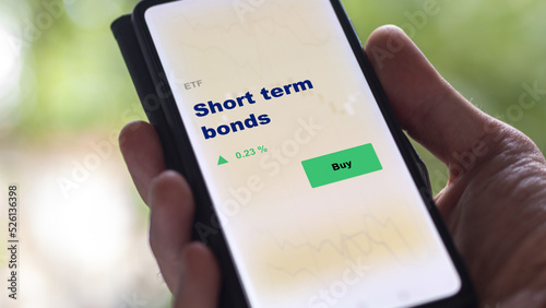 An investor's analyzing the short-term fund bond on screen. A phone shows the ETF's prices short term bonds