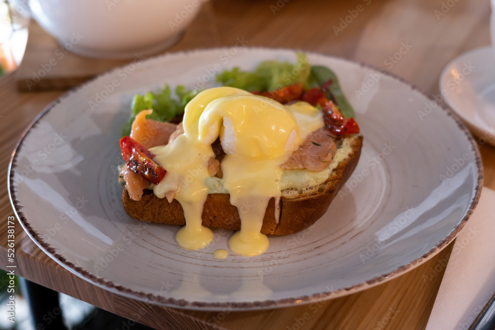 Breakfast sandwich of toasted bread, poached egg, tomato and melted cheese.