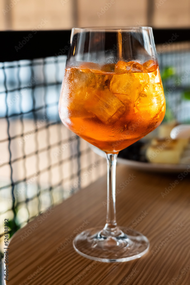 A glass of aperol with ice cubes, an alcoholic drink on a table in a restaurant. A glass of aperol with ice cubes, an alcoholic drink on a table in a restaurant.