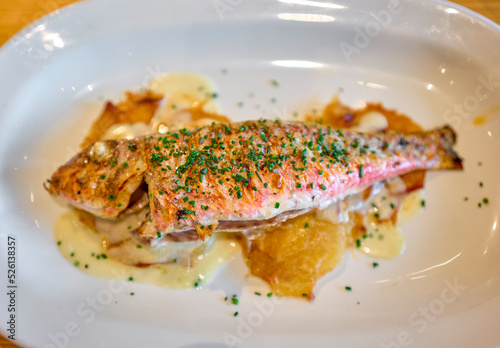 Grilled Red Mullet serverd over baked potatoes and dressing with chives. photo