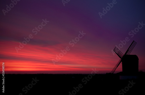 A windmill in Hertfordshire silhouetted by the pink-purple setting sun. 