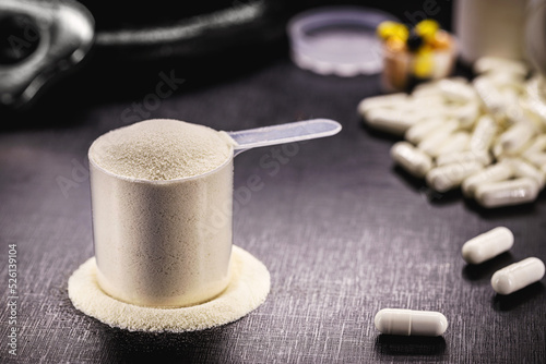 Measuring spoon with creatine or whey, and steroid pills, food supplement, casein cocktail, muscle mass vitamin, plated, bodybuilding concept photo
