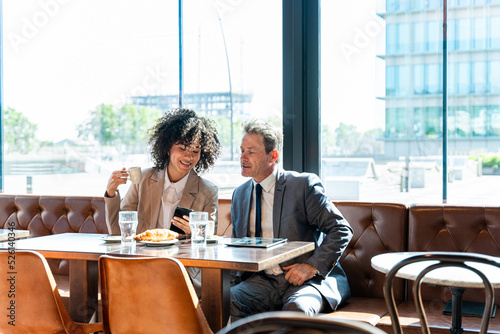 Business meeting in a cafe - Hispanic businesswoman and mature businessman having a conversation in a bar restaurant after work
