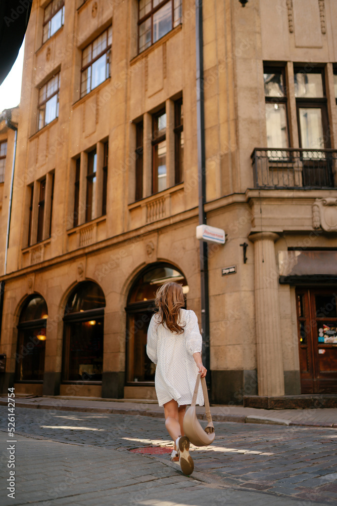 Happy woman walking around the city on a city street. People, fashion, lifestyle, travel and vacations concept.
