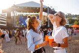 Two young woman  having a great time at a music festival. Happy girlfriends rinking beer and having fun at Beach party. Summer holiday, vacation concept.