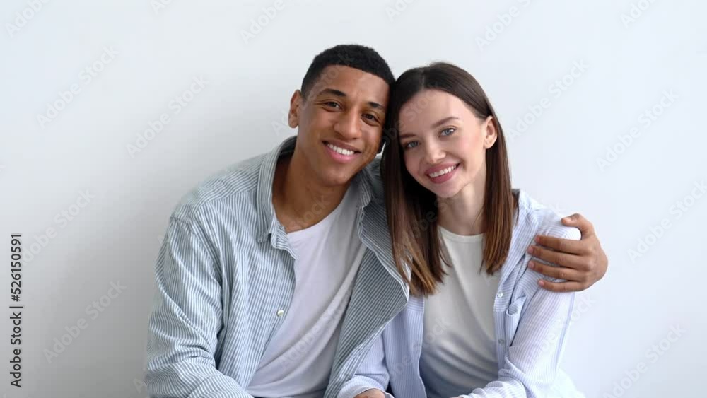 Excited happy multiracial young couple in love, sitting on sofa in living room of their new home between cardboard boxes, they invested in real estate, happy with purchase, looking at camera, smiling Excited happy multiracial young couple in love, sitting on sofa in living room of their new home between cardboard boxes, they invested in real estate, happy with purchase, looking at camera, smiling