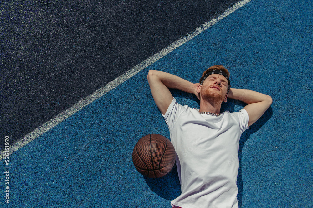 top view of young basketball player relaxing on court near ball top view of young basketball player relaxing on court near ball