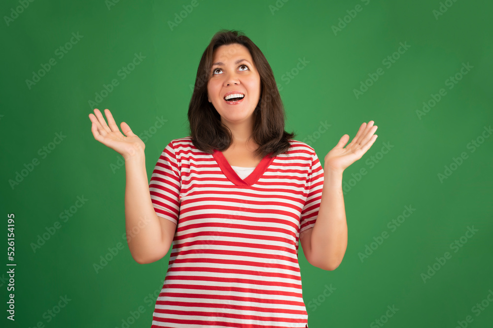 Happy smiling brunette woman in t-shirt looking up on green background Happy smiling brunette woman in t-shirt looking up on green background