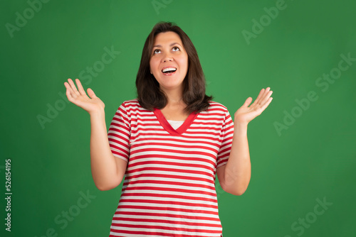 Happy smiling brunette woman in t-shirt looking up on green background