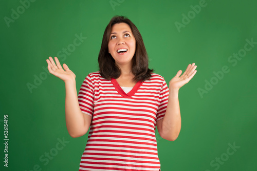 Happy smiling brunette woman in t-shirt looking up on green background