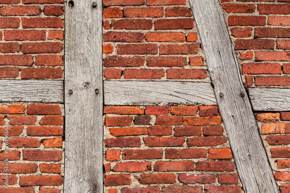 Background texture of an old timber frame wall, consisting of weathered wooden beams and red bakestone bricks, typical for half-timbered architecture, Germany Background texture of an old timber frame wall, consisting of weathered wooden beams and red bakestone bricks, typical for half-timbered architecture, Germany