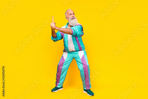 Full length portrait of serious aged person hold shoot bat empty space wear condensed milk tin color clothes isolated on yellow background