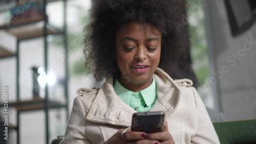 One young black woman having an idea holding smartphone device texting message. African Americna girl using cellphone photo