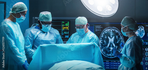 Diverse team of professional medical surgeons perform surgery in the operating room using high-tech equipment. Doctors work to save a patient in a modern hospital. Medicine, technology and healthcare. photo