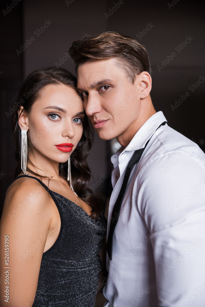 Elegant couple looking at camera at home in evening Elegant couple looking at camera at home in evening
