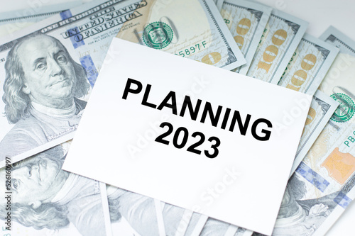 2023planning text on a card against the background of dollar bills, business concept