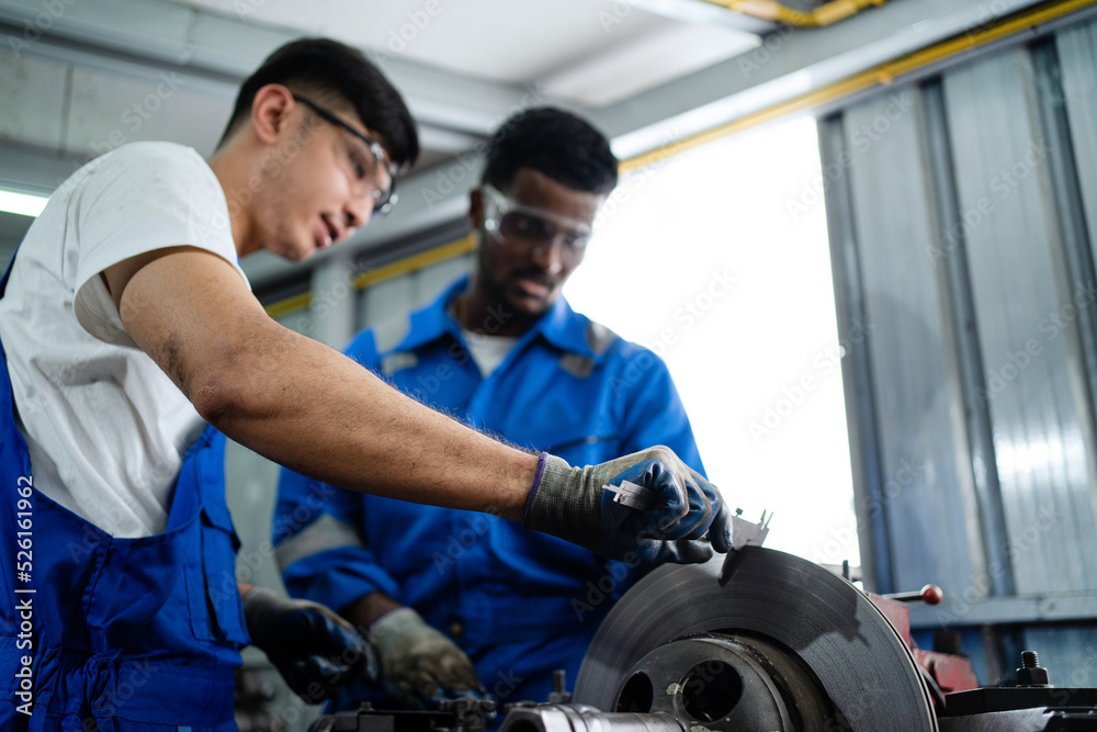 An industrial engineering team wearing safety controls operating a milling machine operating in an industrial plant. A worker uses a Vernier Caliper to measure an object working in a factory.