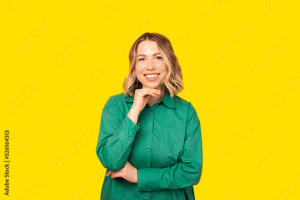 Portrait of a woman with short hair smiling at the camera waring a green shirt standing over yellow background Portrait of a woman with short hair smiling at the camera waring a green shirt standing over yellow background