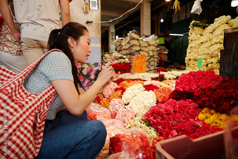 Young woman taking pictures of flowers in Mercado de Jamaica flower
