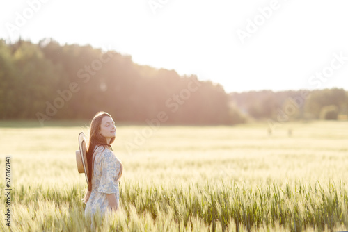 Trendy girl in stylish summer dress feeling free in the field in sunshine. High quality photo