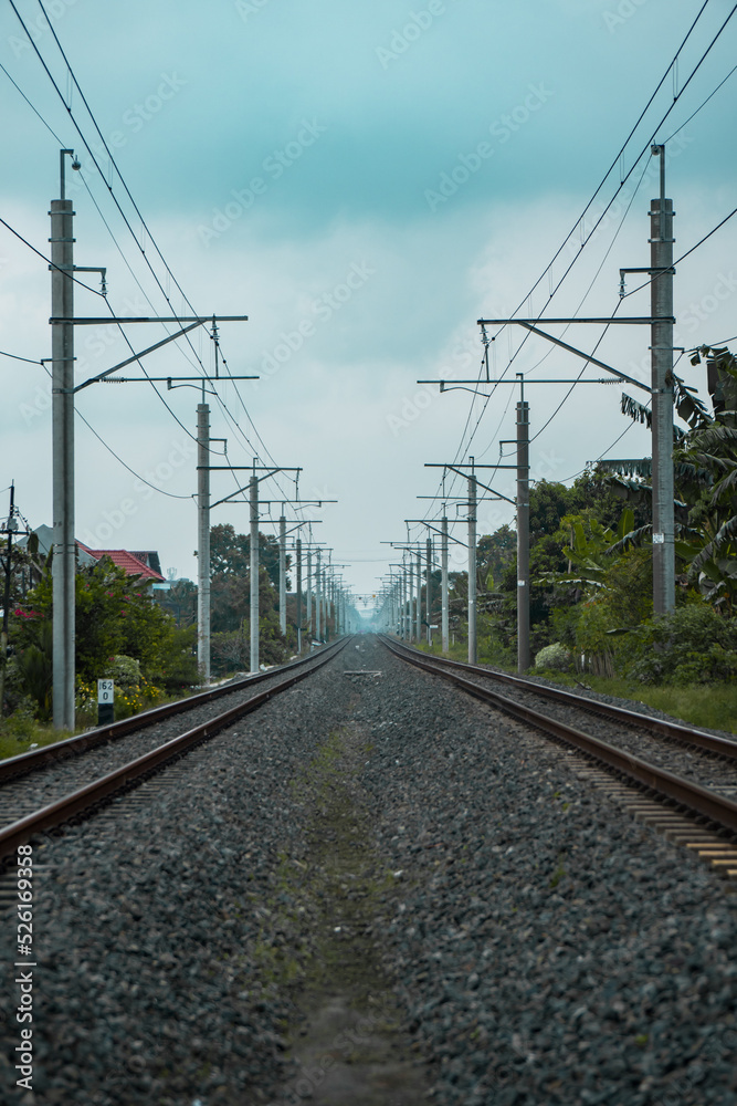 Details of the railroad track made of iron, wood and gravel in a suburban area on a cloudy day in Indonesia