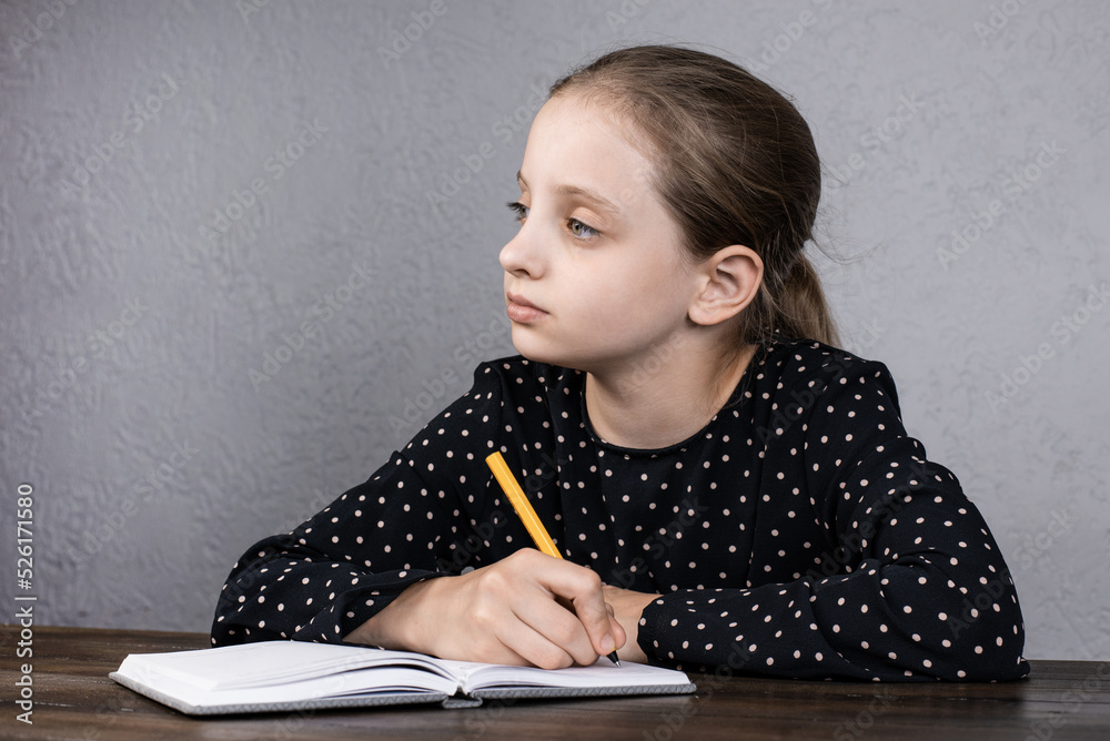 A European girl is sitting at the table doing her homework. Studies. Homework. A European girl is sitting at the table doing her homework. Studies. Homework.