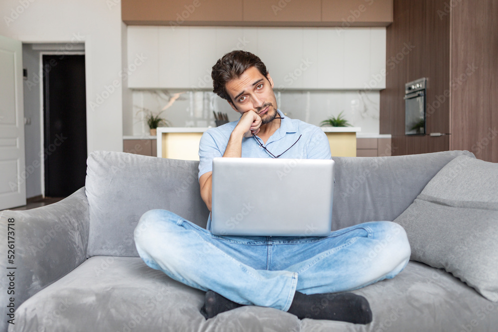 Stressed man sitting on the couch and working on laptop. Work from home and online education concept