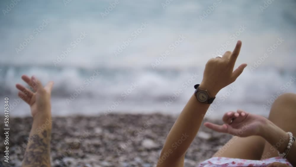 Four women lying on the pebbles and pointing at the sky Four women lying on the pebbles and pointing at the sky