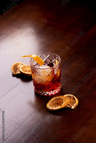 Negroni Cocktail drink closeup with dehydrated oranges on wooden table, portrait