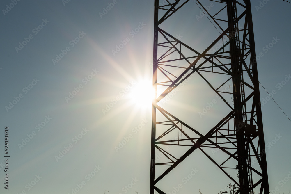 Silhouette of a cell tower with a beautiful sun star
